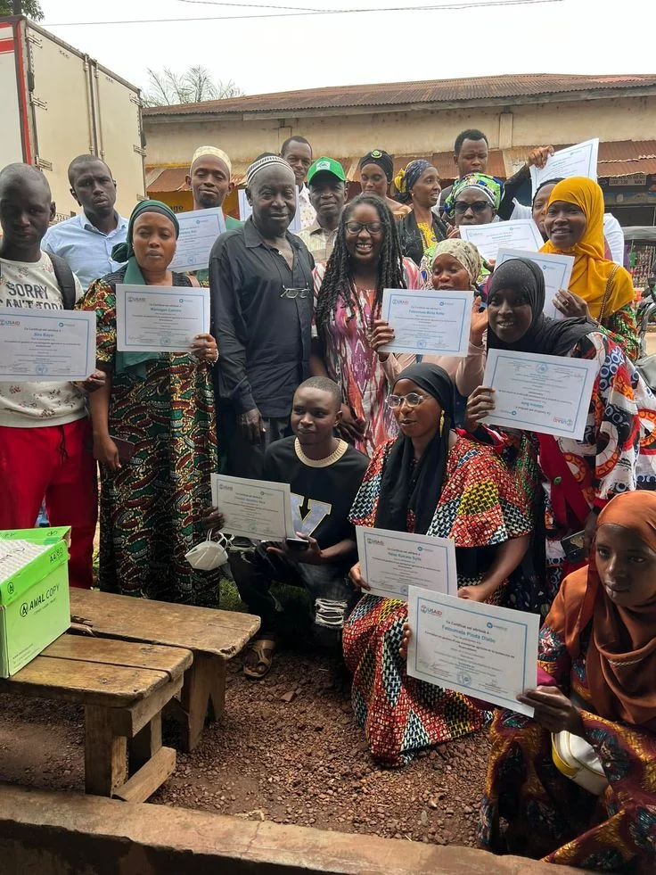 Group holding certificates celebrating outdoors