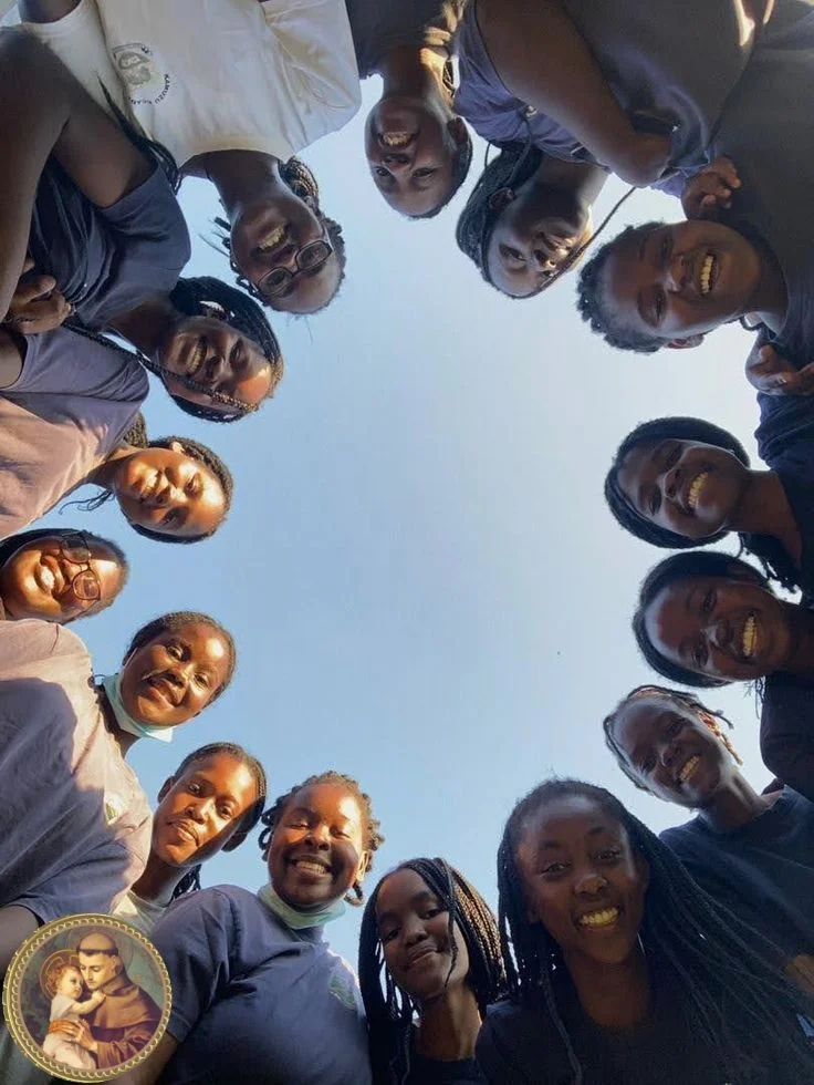 Children forming circle looking down at camera