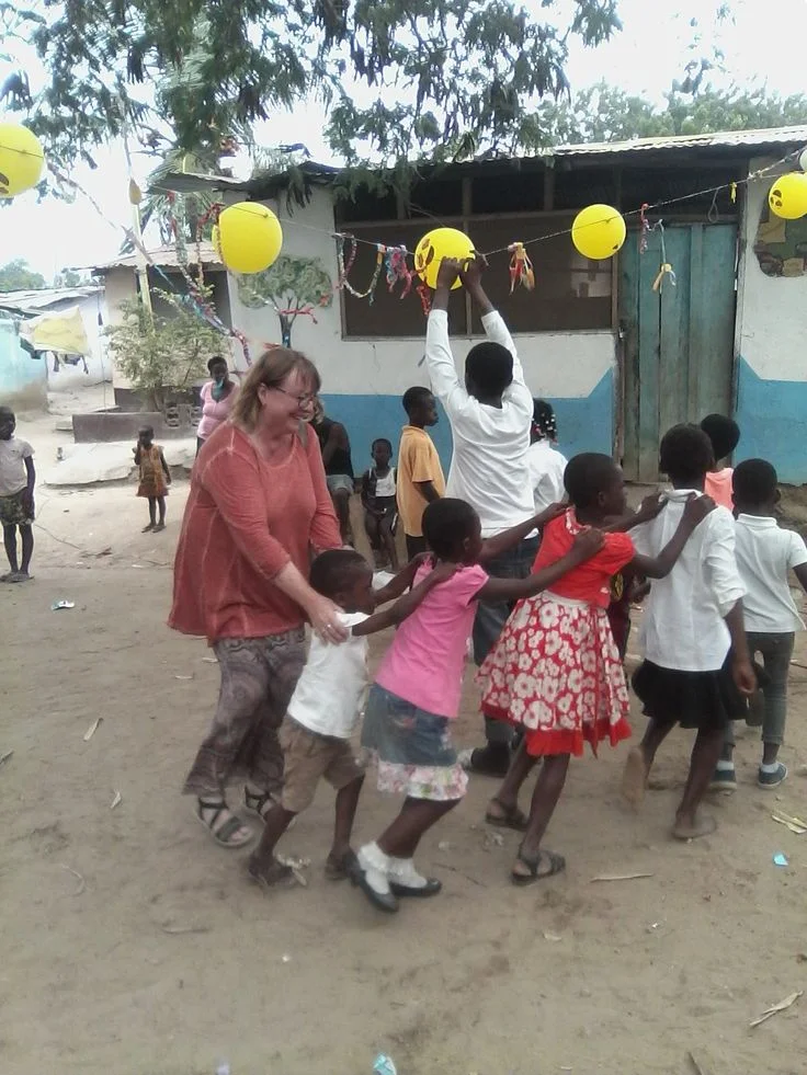 Volunteer playing with children outdoors